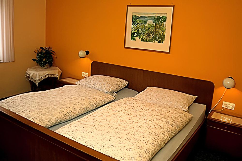 Zimmer mit Doppelbett im rustikalem Stil, die Wände sind orange gestrichen